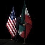 FILE PHOTO: A staff member removes the Iranian flag from the stage after a group picture with foreign ministers and representatives during the Iran nuclear talks at the Vienna International Center in Vienna